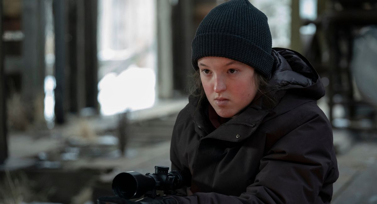 Girl in woods holding a gun Bella Ramsey