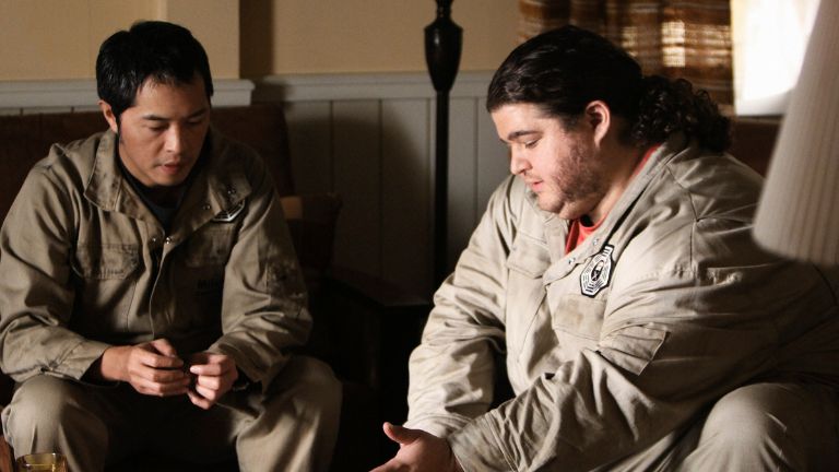 Two men in grey jumpsuits sitting together